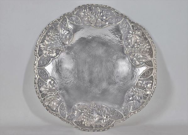 Large round silver fruit bowl with arched edge, chiseled and embossed with embossed grape motifs, supported by three curved feet gr. 800
