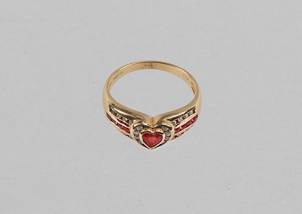 Anello in oro giallo 750 con rubino centrale taglio a cuore affiancato da rubini e diamanti taglio brillante. Gr.4. Rubini Ct. 0,46 circa. Diamanti Ct. 0,20 circa. Misura 14.