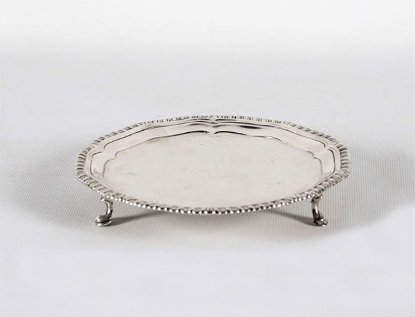 Piccolo salver in argento a forma tonda con bordo baccellato , sorretto da tre piedini ricurvi gr. 190