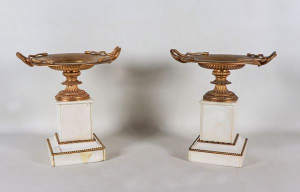 Pair of cup-shaped risers in gilded and chiseled bronze with snake-shaped handles, quadrangular marble bases