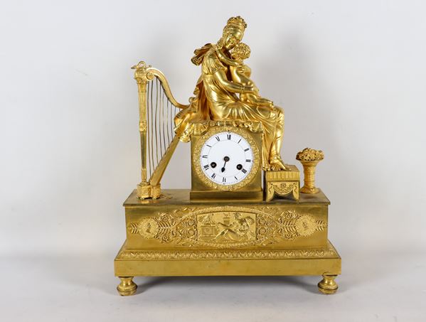 Table clock in gilded and chiseled bronze with sculpture of a noblewoman with little son, harp and vase with flowers
