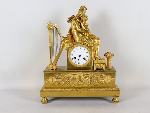 Table clock in gilded and chiseled bronze with sculpture of a noblewoman with little son, harp and vase with flowers