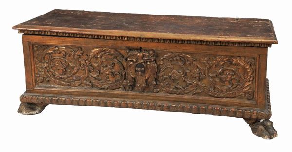 Ancient Umbrian chest in walnut carved with motifs of intertwined volutes and noble coat of arms in the center, legs with lion feet