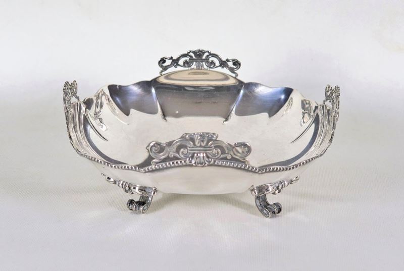 Fruttiera sagomata in argento, cesellata e sbalzata a motivi Luigi XVI e sorretta da quattro pied...