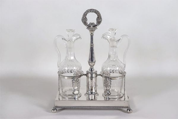 Oliera Impero in argento cesellato e sbalzato a motivi di palmette neoclassiche e corone d'alloro, due ampolle in cristallo, gr. 850