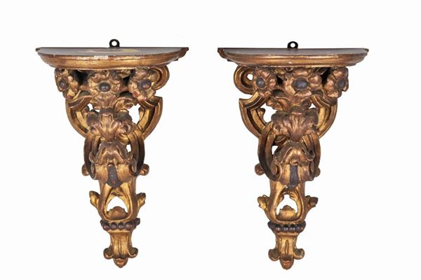 Coppia di mensole da muro, in legno dorato ed intagliato a motivi Luigi XV di volute e fiori