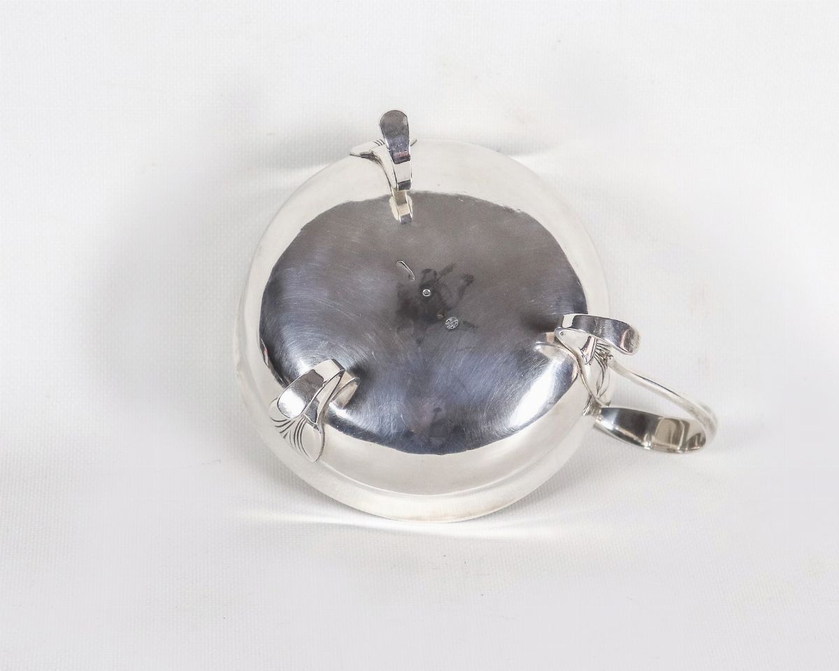 Grande tazza con manico in argento, sorretta da tre piedini ricurvi a motivi Impero, gr. 390