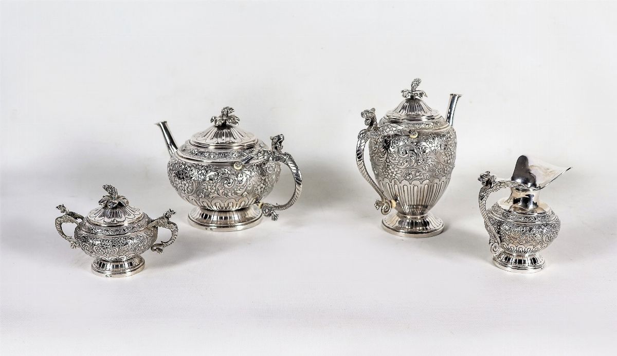 Servizio da tè e caffè in argento cesellato e sbalzato a volute ed intrecci floreali, con manici ...