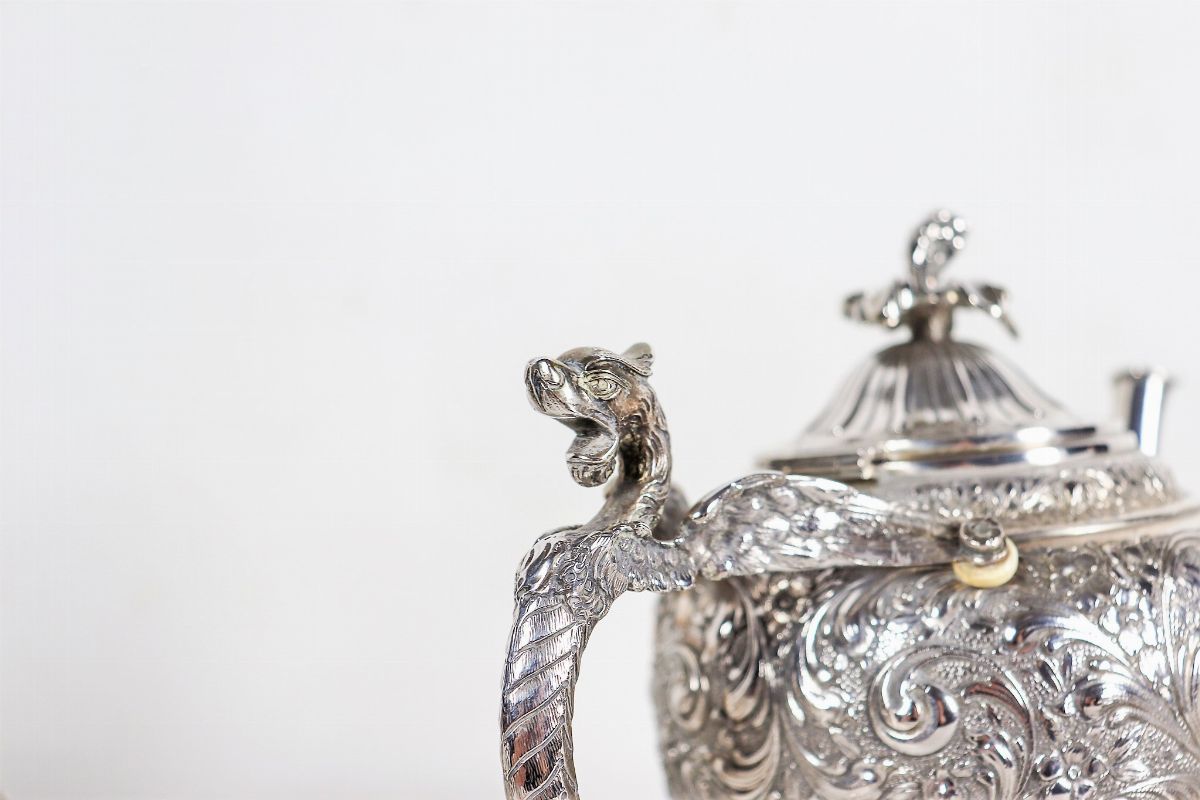 Servizio da tè e caffè in argento cesellato e sbalzato a volute ed intrecci floreali, con manici ...