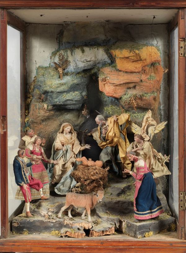 Ancient Neapolitan nativity scene with terracotta puppets and silk dresses, enclosed in a walnut table display case