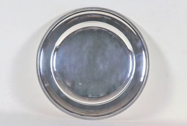 Grande piatto tondo da portata in argento, con bordo cesellato e sbalzato a motivi Impero, gr. 1130