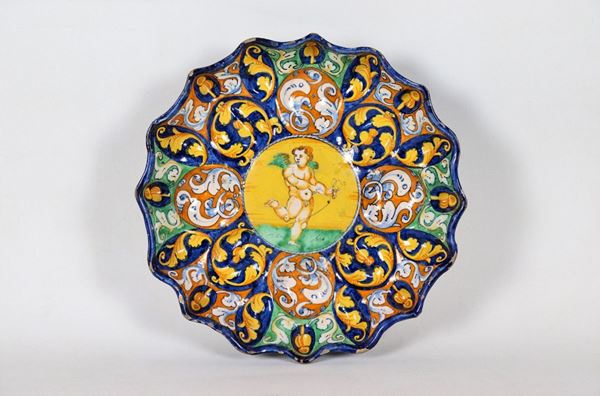 Crespina in maiolica smaltata di Faenza, dipinta e decorata in blu, arancione e giallo con ornati di grottesche e putto centrale