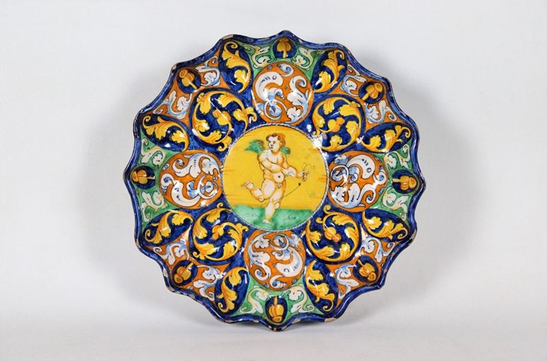 Crespina in maiolica smaltata di Faenza, dipinta e decorata in blu, arancione e giallo con ornati...