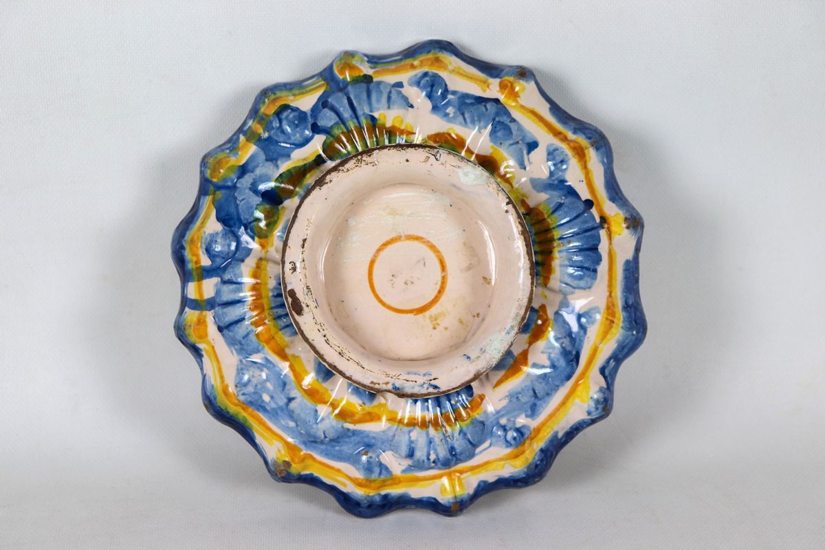 Crespina in maiolica smaltata di Faenza, dipinta e decorata in blu, arancione e giallo con ornati...