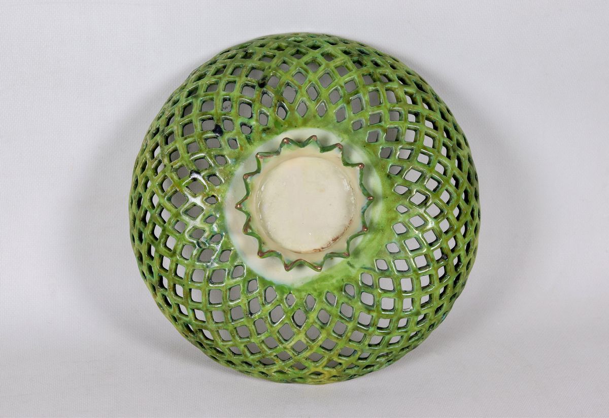 Crespina in maiolica smaltata di Faenza, a forma di cesto traforato, con al centro putto a compen...