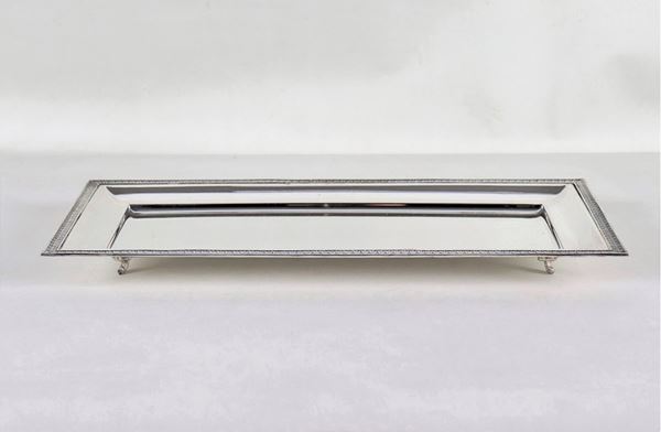 Vassoio rettangolare in argento, con bordo cesellato e sbalzato a motivi Impero, sorretto da quattro piedini ricurvi, gr. 730
