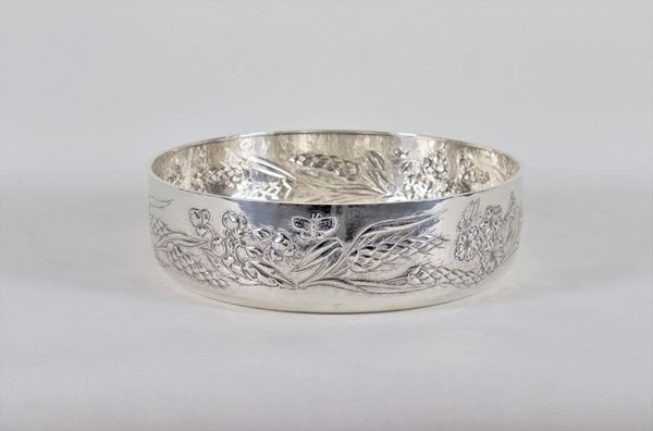 Large round centerpiece in hammered and chiseled silver, with embossed edge in relief with motifs of ears of wheat, fruit and butterflies, gr. 1410