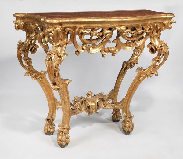 Consolle romana Luigi XV in legno dorato e riccamente intagliato con quattro gambe ricurve riunite da crociera sagomata, piano in legno a finto marmo