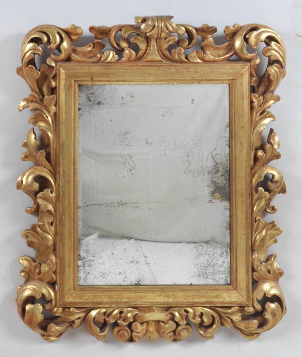 Antica specchiera in legno dorato, riccamente intagliata a motivi di volute di foglie d'acanto, specchio al mercurio