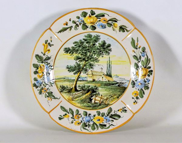 Piatto da muro in maiolica smaltata con decorazioni policrome di mazzetti di fiori e "Paesaggio"