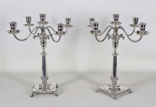 Coppia di candelabri in argento sbalzati e cesellati a motivi Impero, sorretti da piedini leonini, 5 fiamme ciascuno, gr. 2830