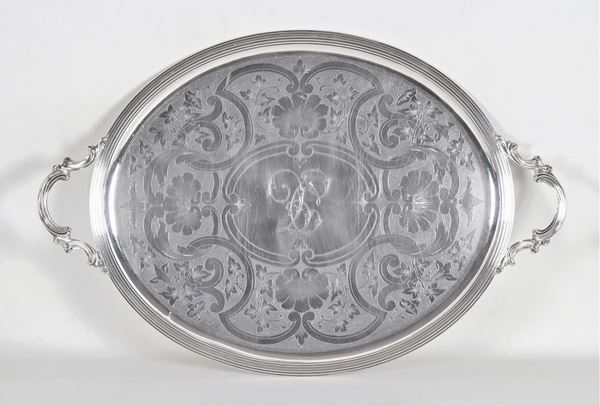 Large oval French tray with two handles, in silvered and embossed metal with a bottom chiseled with floral scrolls and shells and a monogram in the center