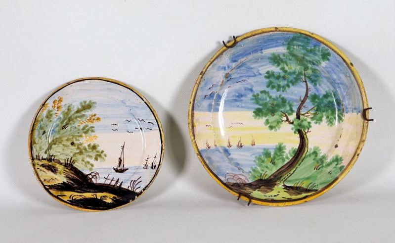Lotto di due piatti in maiolica con decorazioni policrome a motivi di "Marine e paesaggi", uno gr...