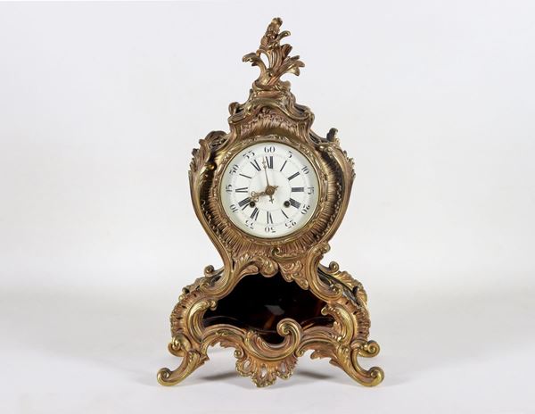 Antique table clock in tortoiseshell and embossed and chiseled gilt bronze with Louis XV motifs, dial in white enamel with Roman numerals