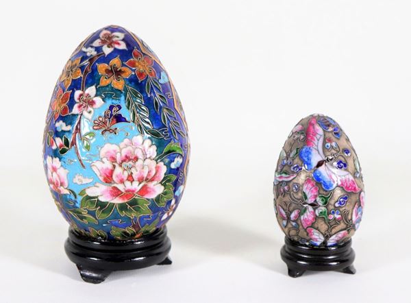 Lotto di due uova cinesi in smalto cloisonné, interamente decorate e policromate a motivi di fiori esotici e farfalle, una grande e una piccola