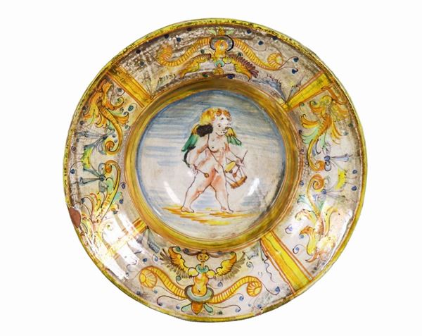 Antique Italian majolica plate with arabesque decorations in yellow and light blue, in the center the figure of "Putto"