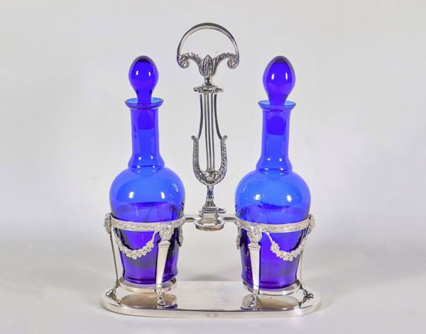 Primo Impero Roman oil cruet, in chiseled and embossed silver with neoclassical motifs of floral garlands and masks, lyre-shaped handle and two cobalt blue crystal ampoules, gr. 500