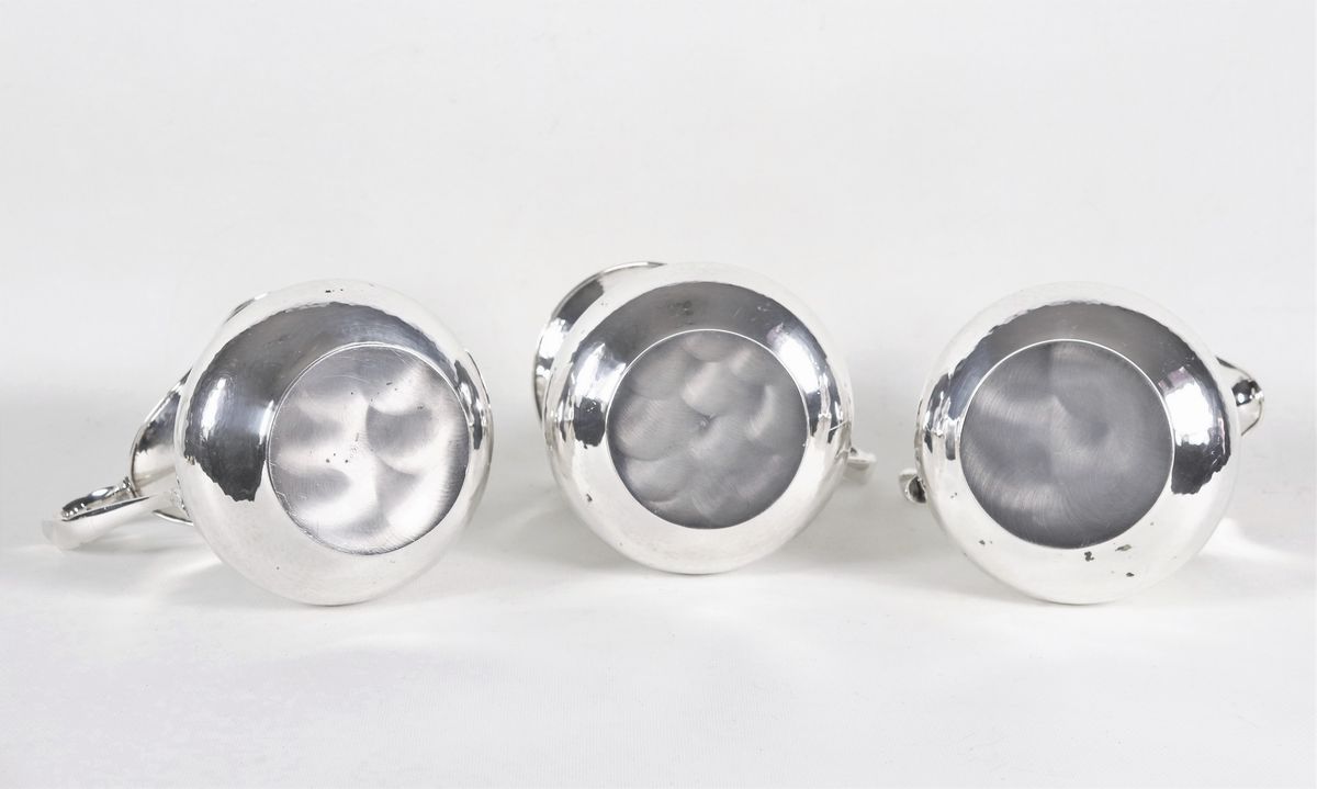 Lotto di tre brocche per acqua in argento martellato con manici ricurvi, gr. 1690