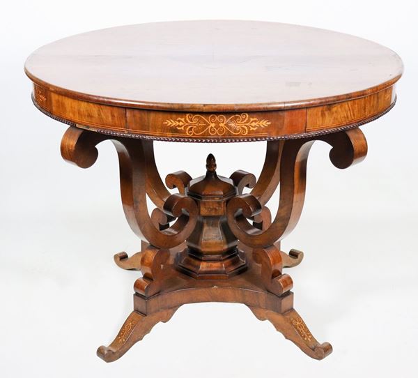 Charles X period Tuscan center table in walnut, round shape with inlaid top underband and secret drawer, base with four arched legs joined by central cross