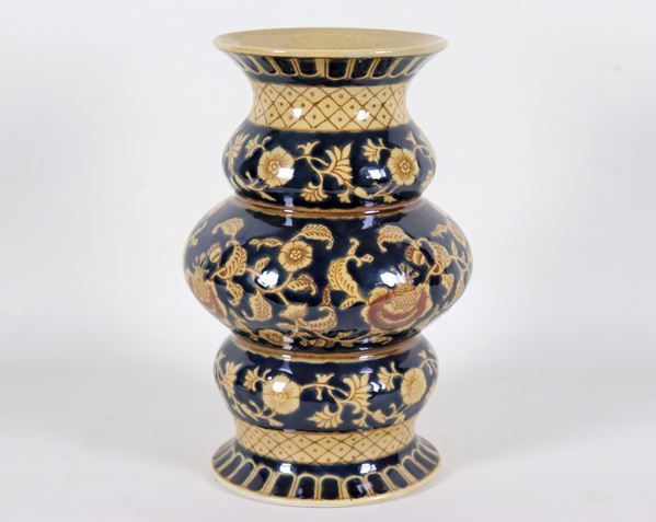 Vase in porcelain and glazed ceramic with a rounded shape, with floral decorations on a blue background