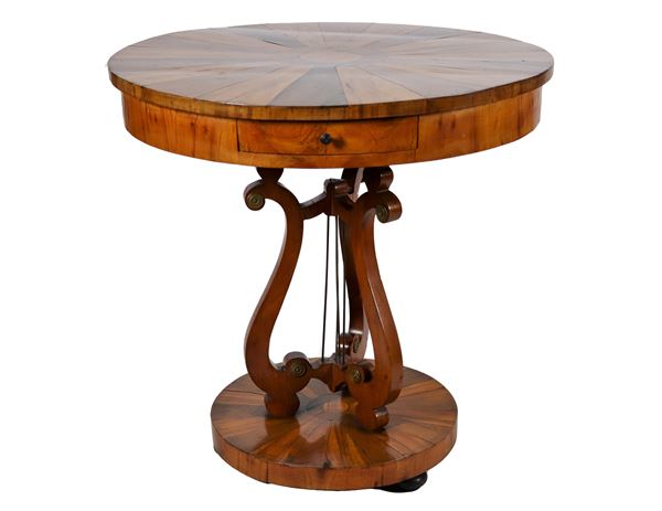 Round-shaped Emilian coffee table, in walnut and olive briar, with wedge-veneered top and central drawer, lyre-shaped base supported by a wedge-veneered round top