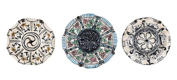 Lotto di tre piatti da muro in maiolica smaltata San Marco, con decorazioni variopinte a motivi di gondole, fiori gialli e neri e grappoli d'uva