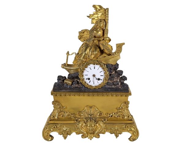 Pendola da tavolo francese in bronzo dorato, sbalzato e cesellato, sormontata da gruppo scolpito "Barca con dama e stendardo", quadrante in smalto bianco entro corona d'alloro