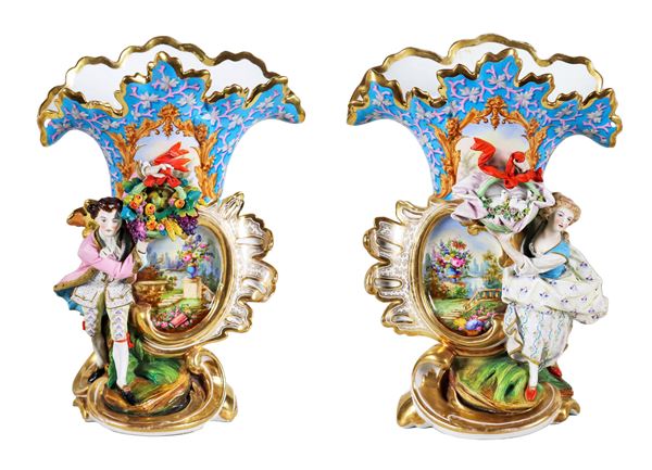 Coppia di antichi vasi "a cartoccio" Luigi Filippo in porcellana, con sculture a rilievo "Dama e cavaliere", al centro medaglioni dipinti a motivi di paesaggi e mazzetti di fiori, lumeggiature in oro zecchino