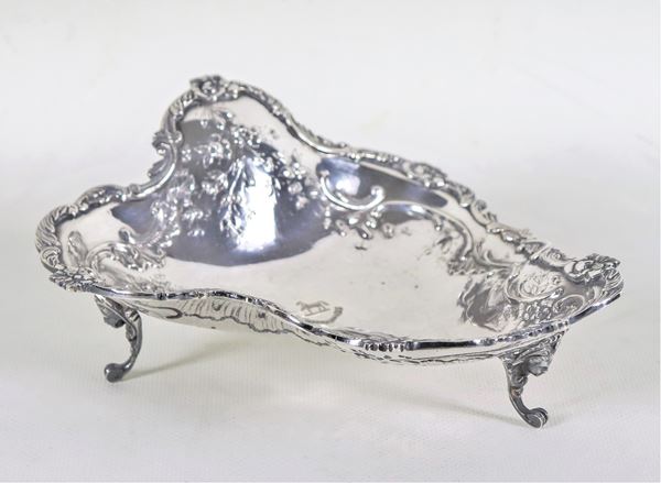 Portabonbon sagomato in argento cesellato e sbalzato a volute ed intrecci floreali, sorretto da tre piedini ricurvi con teste di cariatidi, gr. 260