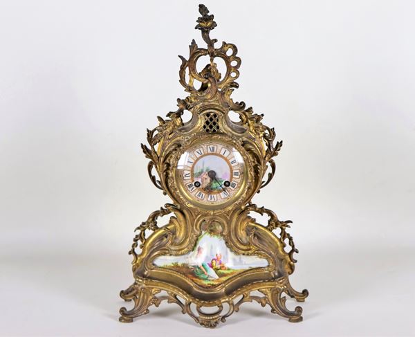 Antica pendola da tavolo francese di linea Luigi XV in bronzo dorato, con decorazioni in porcellana smaltata e dipinta a motivi di scena galante e paesaggio, quadrante con cifre romane