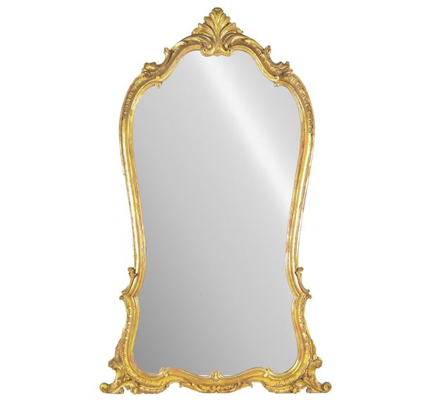French mirror of the Louis XV line with arched shape, in gilded wood and carved with motifs of volutes and curls