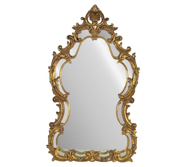 Specchiera francese di linea Luigi XV a forma centinata, in legno dorato e intagliato a motivi di volute e ricci