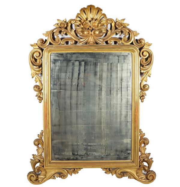 Louis Philippe Neapolitan mirror in gilded and carved wood with motifs of scrolls of acanthus leaves, curls, flowers and leaves, in the center of the shell cymatium. Mercury mirror