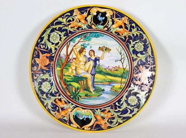 Piatto da parata in maiolica smaltata e invetriata, marcato Palatino Ars - Borzelli Roma, interamente variopinto a rilievo con scena mitologica al centro