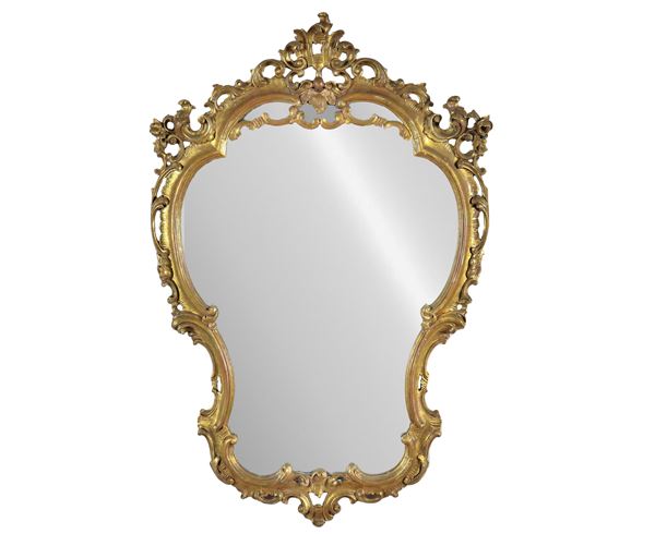 French mirror of the Louis XV line with arched shape, in gilded wood and carved with motifs of volutes and curls