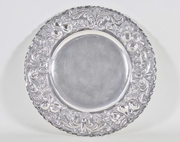 Piatto tondo in argento, con bordo cesellato e sbalzato a motivi di frutta a rilievo, gr. 520