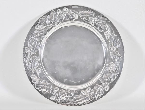 Piccolo piatto tondo in argento, con bordo cesellato e sbalzato a motivi di ghiande e foglie, gr. 270