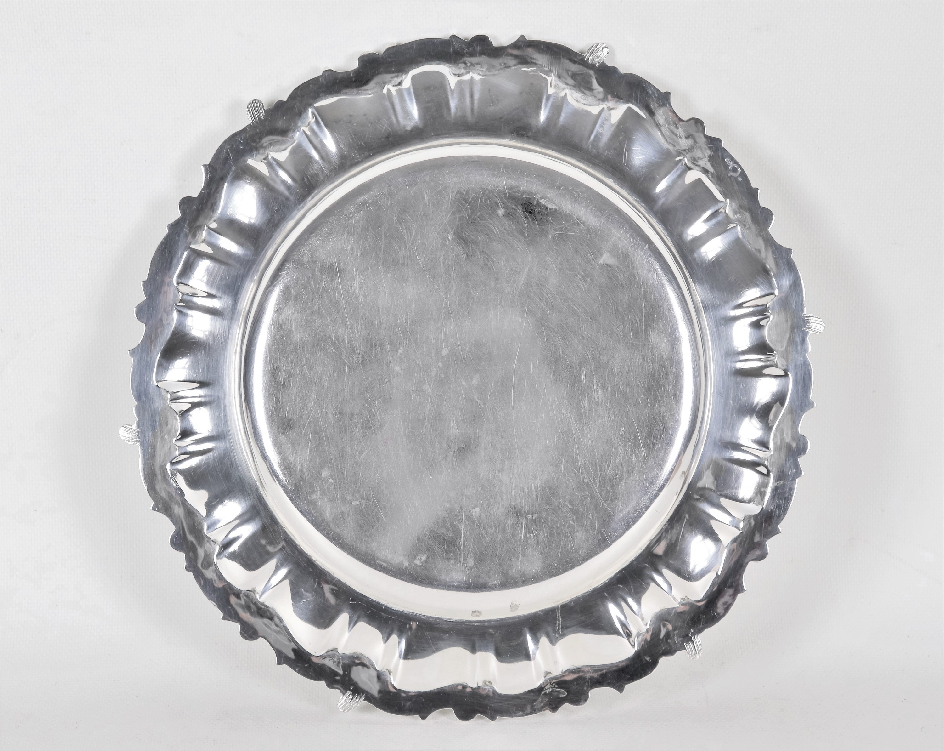 Piatto tondo in argento con bordo cesellato e sbalzato a volute di foglie d'acanto, gr. 760