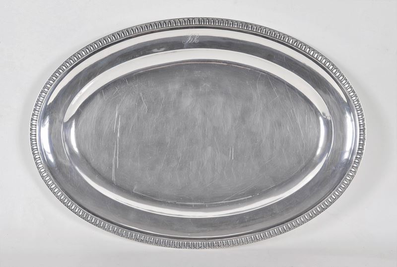 Grande piatto ovale da portata in argento, con bordo cesellato a palmette neoclassiche e monogram...