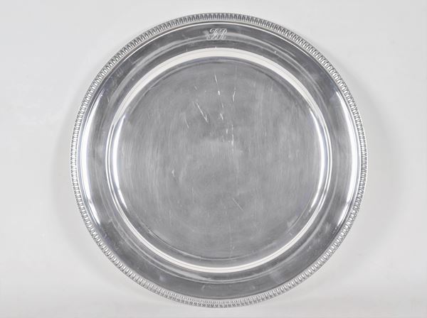 Large round silver serving plate, with chiselled edge with neoclassical palmettes and engraved monogram, gr. 1210